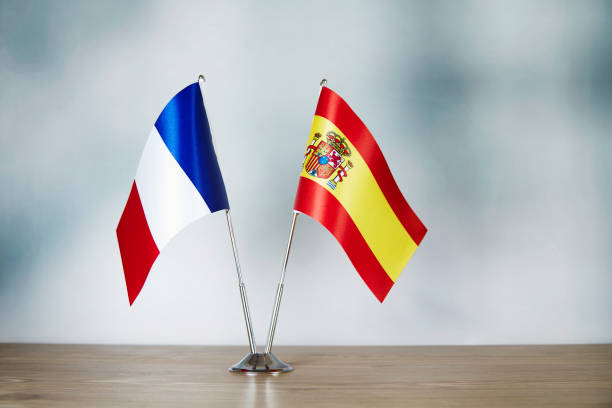 French and Spanish flag standing on the table with defocused background